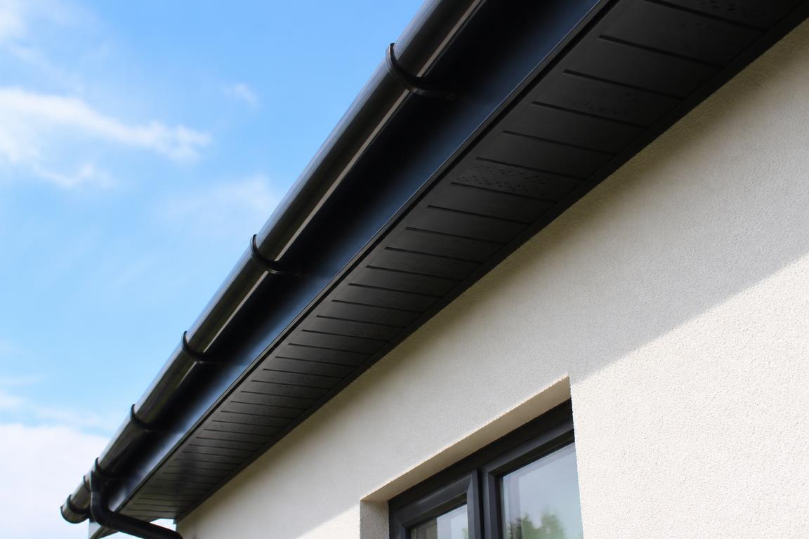 Brand new black uPVC fascia, soffit and guttering along a house eaves