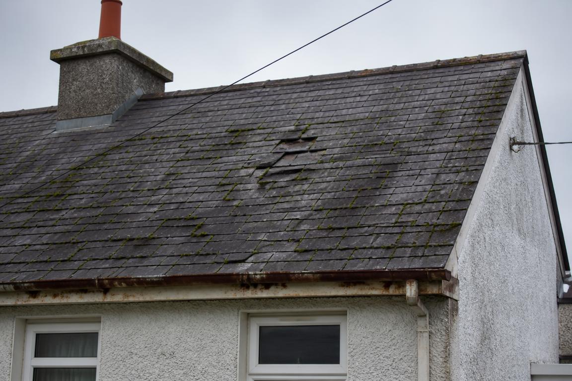 Old slate roof with slipped tiles and moss before repair work
